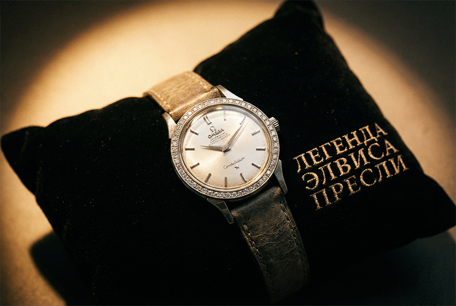 Винтажные часы Omega с бриллиантовым безелем на черной подушечке с золотой вышивкой 'Легенда Элвиса Пресли'.